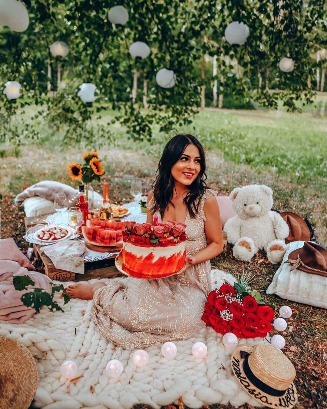a woman sitting on grass holding her cake